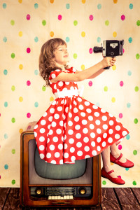 Child playing at home. Girl holding retro camera. Cinema concept
