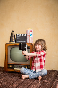 Child playing at home. Kid taking selfie with retro camera. Cinema concept